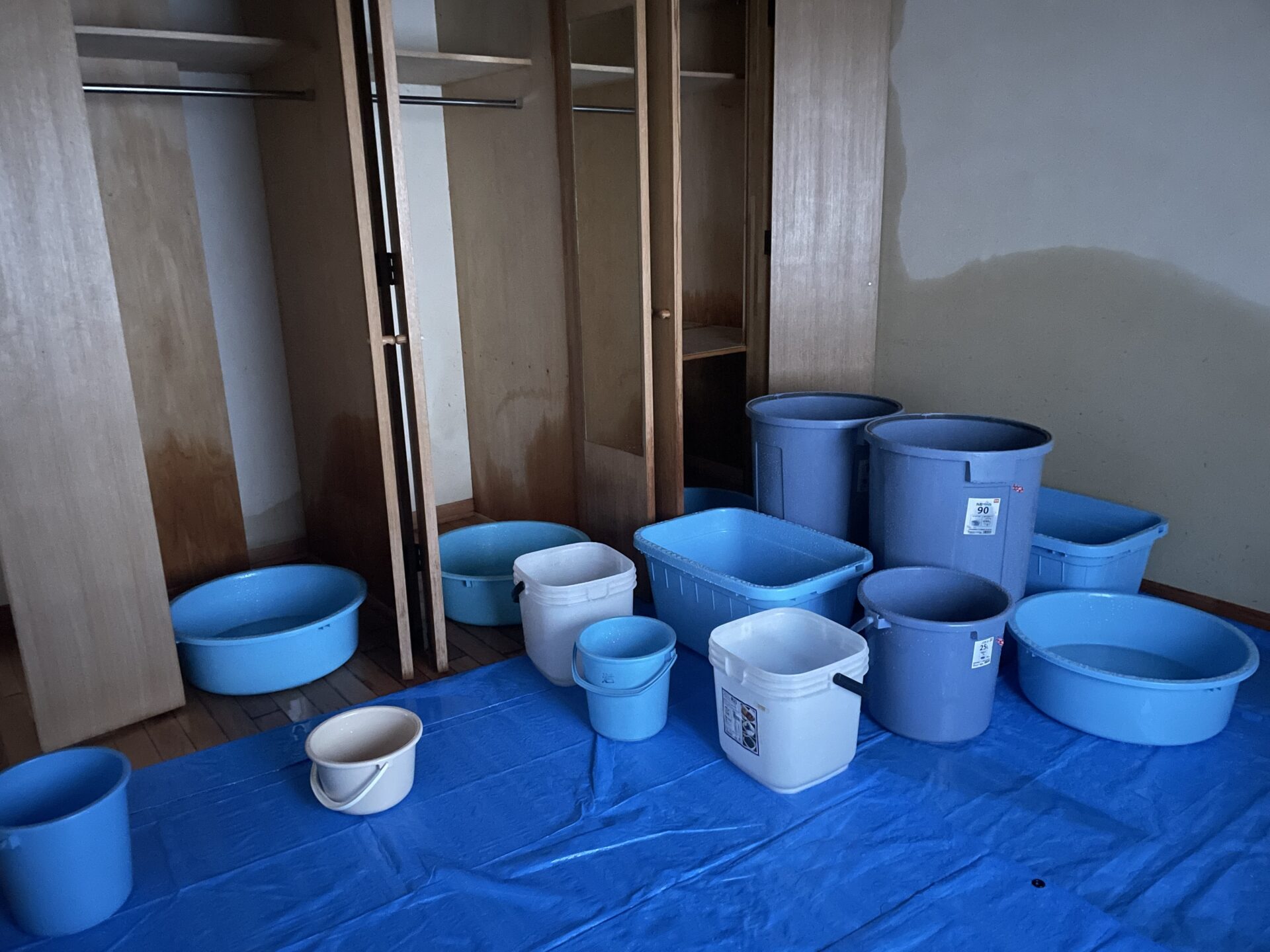 屋根からの突然の雨漏りで室内に大量のバケツを置いて凌ぐ様子