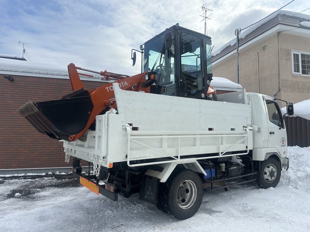小型のホイルローダーと４tスライド式ダンプの組み合わせで安全に札幌市内どこでも排雪が可能な体制です（マツモトルーフ）