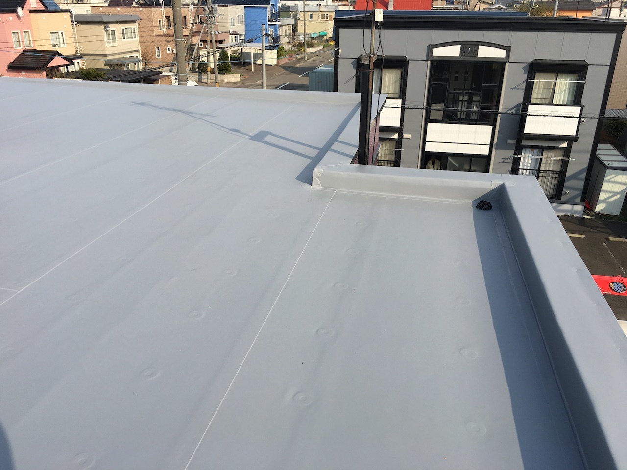 シート防水施工後の屋根全景と排水口