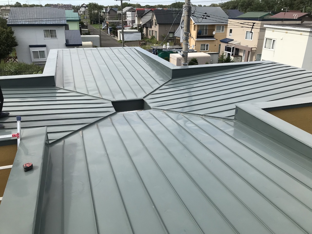 四方の屋根面が中央の排水枡へ集まる十字型の板金屋根