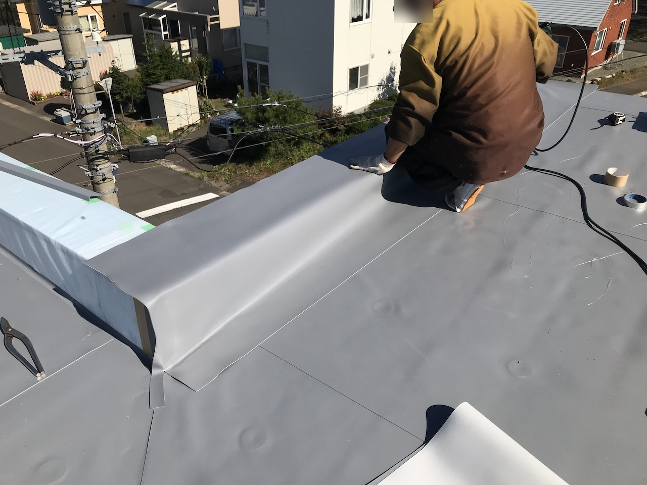 屋根面から立ち上がりと笠木へ防水シートを施工する工程