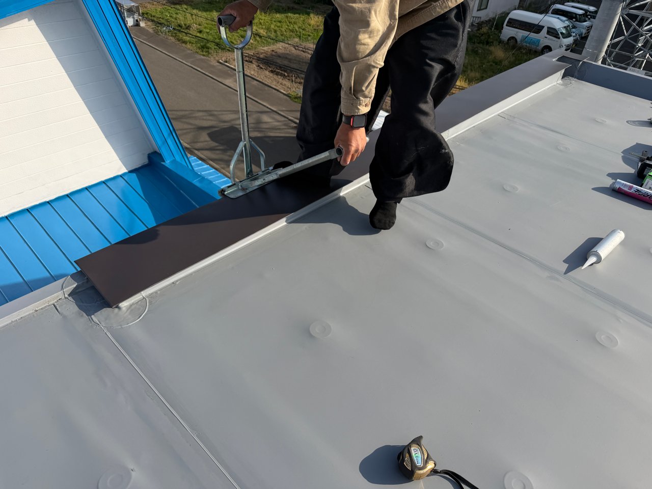 笠木に仕上げの鋼板を取り付ける作業。