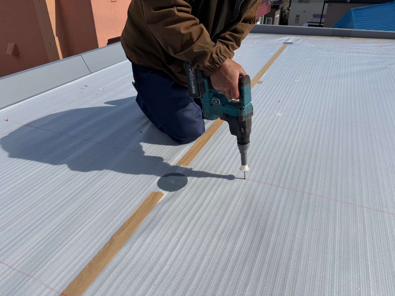 本屋の防水シート固定用ディスク盤の取り付け位置に穴をあける作業。