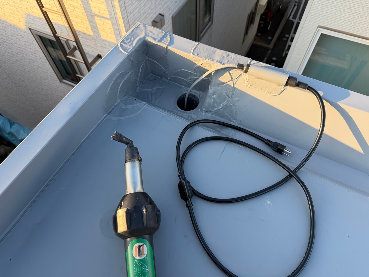 北西角の排水ドレン付近に排水路ヒーターを設置する工程。