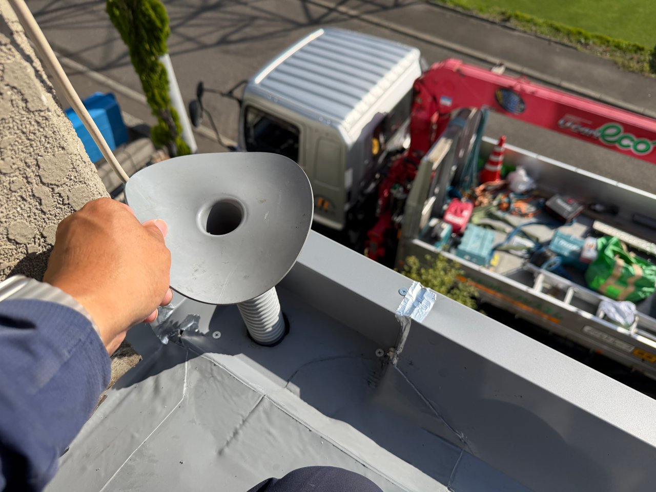 バルコニー屋根の排水口に新しいドレンを合わせる工程。